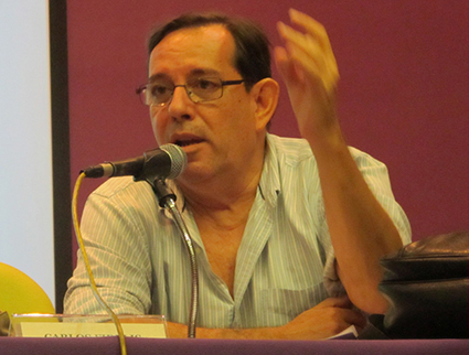 Carlos Fidelis de óculos fala ao microfone em evento