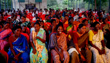 grupo de moças indianas com roupas tipicas sentadas em cadeiras, rindo, assistem peça de teatro 